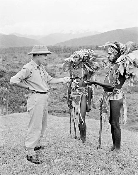 HistPOM-30-1950.jpg - Assistant District Officer Bill Tomasetti offers tobacco to two men in tribal dress, possible as payment for a sing-sing, Papua New Guinea, 1950 (source: National Archives of Australia; http://www.naa.gov.au/collection/snapshots/on-patrol-in-papua-new-guinea/sogeri-barracks.aspx; accessed: 4.2.2013)